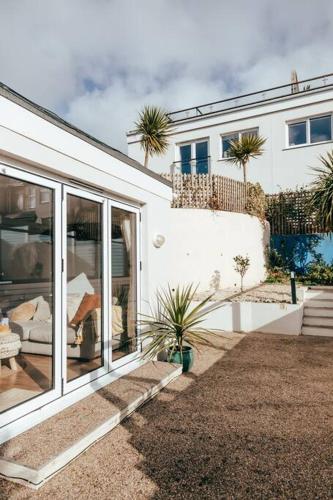a white house with palm trees in front of it at The Hideout - Newquay - Fully Stocked Eco Escape in Newquay