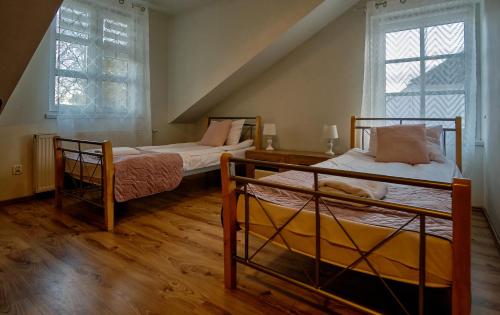 two beds in a room with two windows at Bohema Restauracja i Noclegi in Supraśl