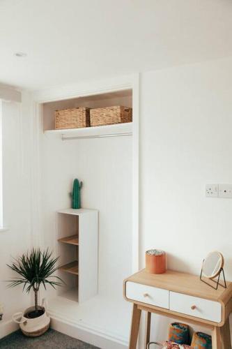 a white room with a table and a plant at The Hideout - Newquay - Fully Stocked Eco Escape in Newquay