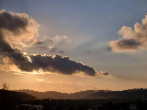 a cloudy sky at sunset with mountains in the background at יחידת אירוח נעם in Netiv HaLamed He