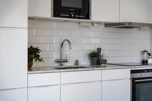 a kitchen with white cabinets and a sink at Beautiful and modern accommodation near Stockholm City in Stockholm