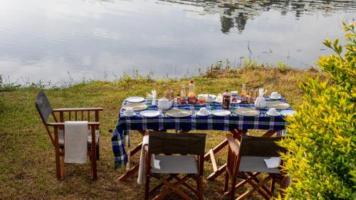 a table with a blue table cloth and chairs next to a lake at Lake Chahafi Resort in Kisoro