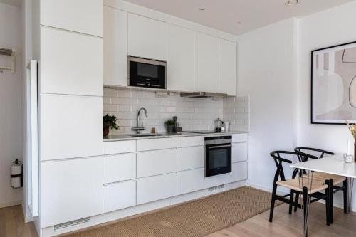 een keuken met witte kasten en een tafel met stoelen bij Beautiful and modern accommodation near Stockholm City in Stockholm