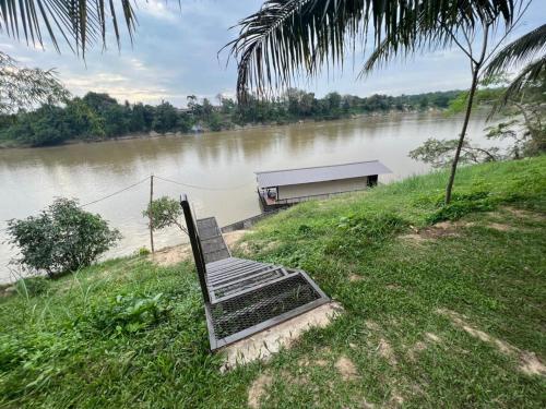 a bench sitting on the side of a river at Chalet Terapung Laman Tok Ayah Temerloh in Temerloh