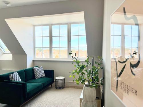 a living room with a green couch and windows at The Apartments Lytham Square in Lytham St Annes