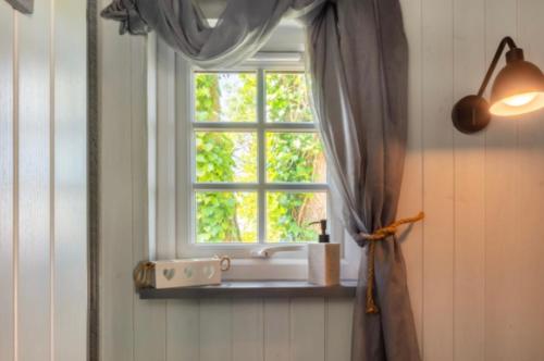 een raam in een kamer met een gordijn bij Nefoedd Romantic Shepherds Hut in Swansea