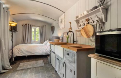 a bedroom with a bed and a kitchen with a television at Nefoedd Romantic Shepherds Hut in Swansea