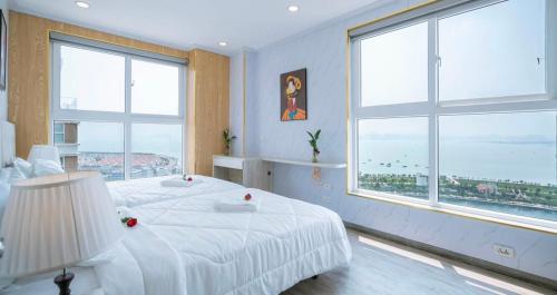 1 dormitorio con cama blanca y ventanas grandes en Homestay Ha Long Luxury 3 bedroom (ocean view), en Ha Long