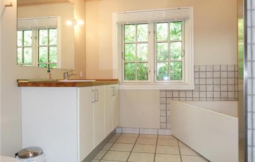 y baño con bañera, lavabo y ventanas. en Gorgeous Home In Aakirkeby With Wifi en Vester Sømarken