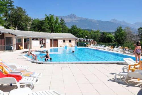 una gran piscina con sillas y gente en ella en Vue imprenable sur Lac de Serre-Ponçon à Chorges : appt prestige 8 pers, en Chorges