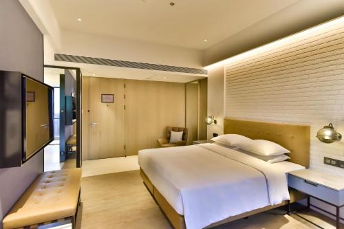 a bedroom with a large white bed and a desk at Four Points by Sheraton Taipei Bali in Bali