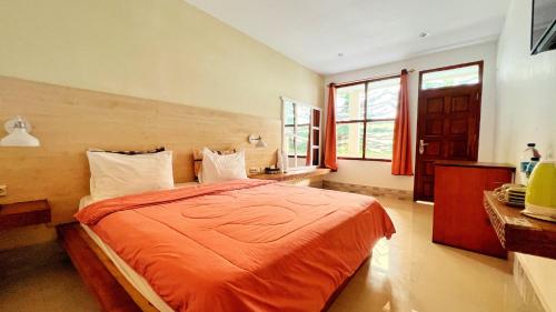 sypialnia z łóżkiem z pomarańczowym kocem w obiekcie Centro Bajo Hotel & Resto w Labuan Bajo