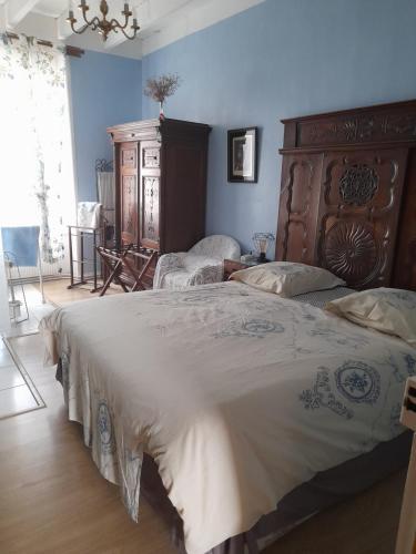 a bedroom with a large bed with a wooden headboard at La Mare aux Fées in Huelgoat