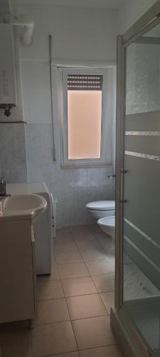 een badkamer met een wastafel, een toilet en een raam bij La casa di Cri con servizio spiaggia incluso! in San Benedetto del Tronto