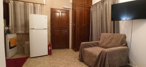 uma sala de estar com uma cadeira e um frigorífico em Villa Maria em Kalymnos