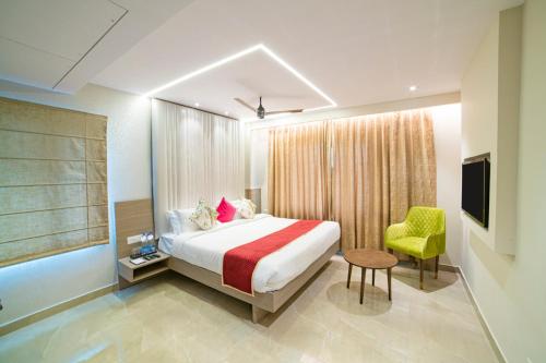 a bedroom with a bed and a chair and a television at The Beacon Hotel Visakhapatnam in Visakhapatnam