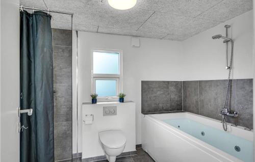ein Bad mit einer Badewanne, einem WC und einem Fenster in der Unterkunft Amazing Home In Assens With House Sea View in Assens