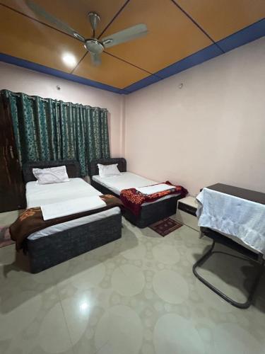 a room with two beds and a ceiling fan at ROOP AMRIT GUEST HOUSE in Agartala