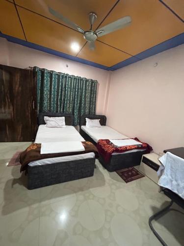 a bedroom with two beds and a ceiling fan at ROOP AMRIT GUEST HOUSE in Agartala