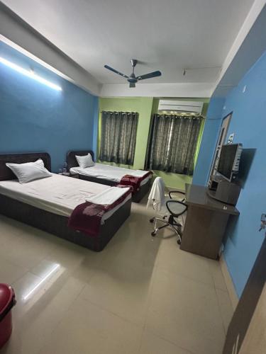 two beds in a room with a television and a desk at ROOP AMRIT GUEST HOUSE in Agartala