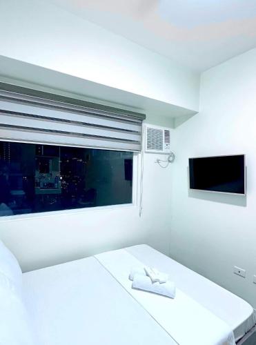 a white bedroom with a bed and a window at Urban Nest PH in Manila