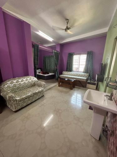 a living room with purple walls and a bed and a sink at ROOP AMRIT GUEST HOUSE in Agartala