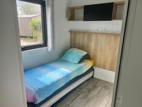 małe łóżko w małym pokoju z oknem w obiekcie Mobilhome Camping Biscarrosse 5 étoiles bord du lac w mieście Biscarrosse