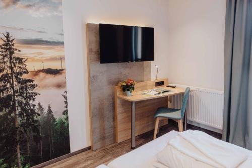 a hotel room with a desk and a tv on a wall at Pascals Ruhestube in Mörsdorf
