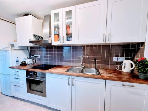 a kitchen with white cabinets and a sink at Lovely House with garden in London