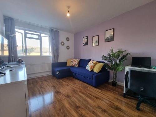 a living room with a blue couch and a television at Lovely House with garden in London