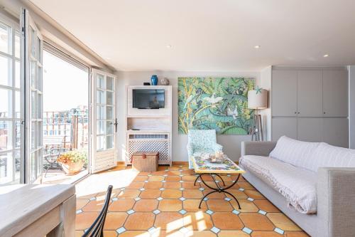 a living room with a couch and a tv at Le Golfe Bleu - Havre de paix en bord de plage in Roquebrune-Cap-Martin