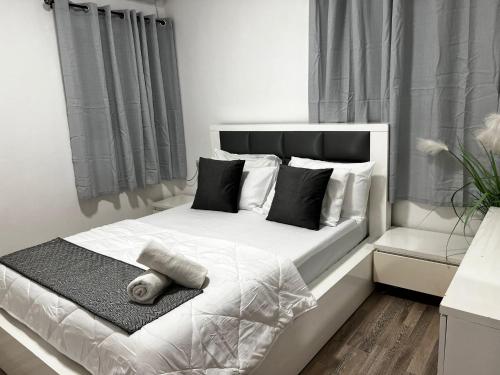a bedroom with a white bed with black and white pillows at Spat Vip Apartment in Bat Yam