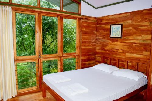 Solitude Munnar في مونار: غرفة نوم مع سرير في غرفة مع نوافذ