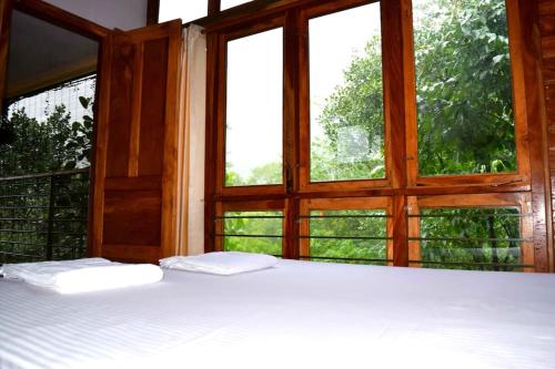 Solitude Munnar في مونار: سرير في غرفة مع وسادتين أمام النافذة