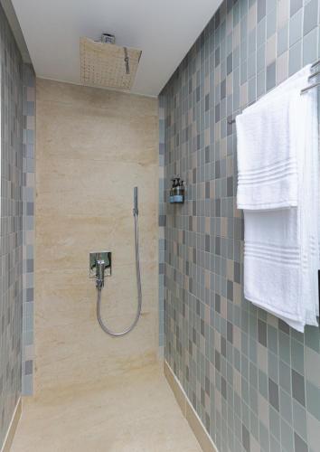 a bathroom with a shower with blue and gray tiles at Ewaa Express Hotel - Al Jouf in Sakakah