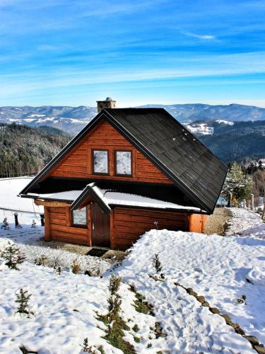 a log cabin with snow on the roof at Domek u Johnnego in Piwniczna-Zdroj
