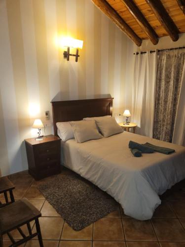 Habitaciones La Flamenka في روندا: غرفة نوم بسرير كبير مع طاولتين ومصباحين