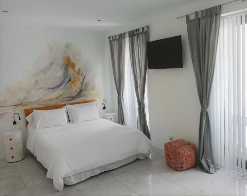 a bedroom with a white bed and a tv at OPUNTIA Hotel Boutique in Mijas