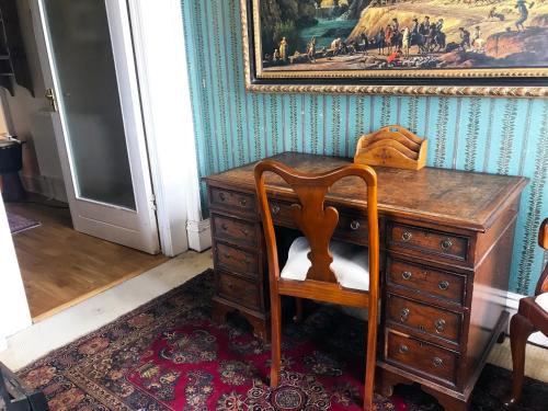 a wooden desk with a chair and a painting on the wall at Grand top floor apartment in the Royal Bank House in Maybole