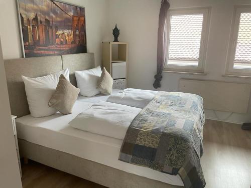 Schlafzimmer mit einem Bett mit weißer Bettwäsche und Kissen in der Unterkunft Ferienwohnung An der alten Weed in Bad Windsheim