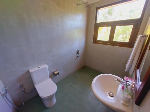 a bathroom with a toilet and a sink and a window at Atrium Hiriketiya in Hiriketiya