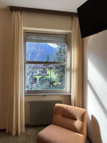 a room with a chair and a large window at Hotel Diana in Riva del Garda