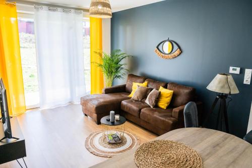 ein Wohnzimmer mit einem braunen Sofa und einem Tisch in der Unterkunft L'aparté - Centre ville Lens - Gare in Lens