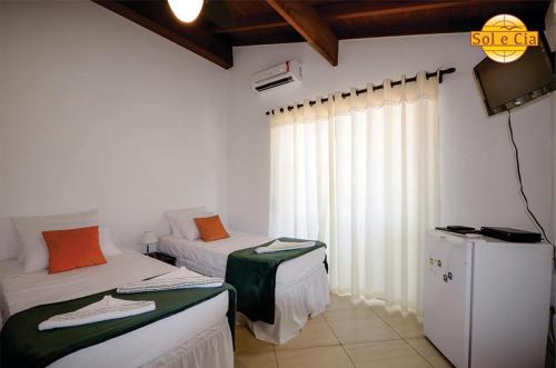 a room with two beds and a television in it at Pousada Sol e Cia Tur in Caraguatatuba