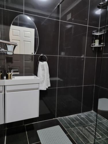 a black bathroom with a sink and a mirror at 11-on-RobRoy calming space with 3 bedrooms&pool in Hillcrest