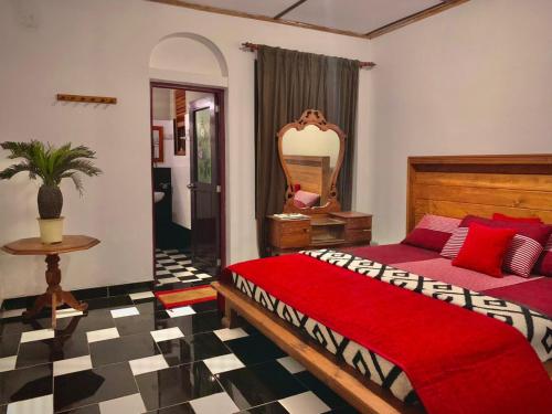 a bedroom with a red bed and a mirror at Diyon Bungalow in Bandarawela