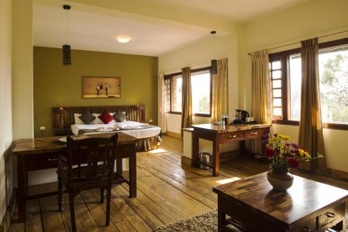 a room with a bed and a desk and a table at Destiny - The Farm Resort in Ooty