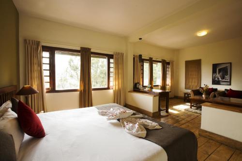 a bedroom with a large white bed and windows at Destiny - The Farm Resort in Ooty