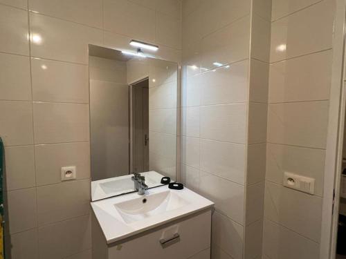 a white bathroom with a sink and a mirror at Appartement idéalement placé in Villeparisis
