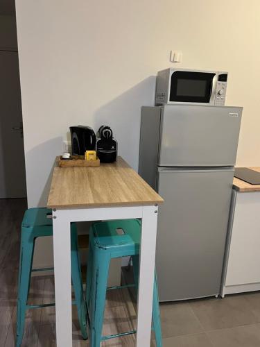 een keuken met een tafel, een magnetron en een koelkast bij Appartement idéalement placé in Villeparisis